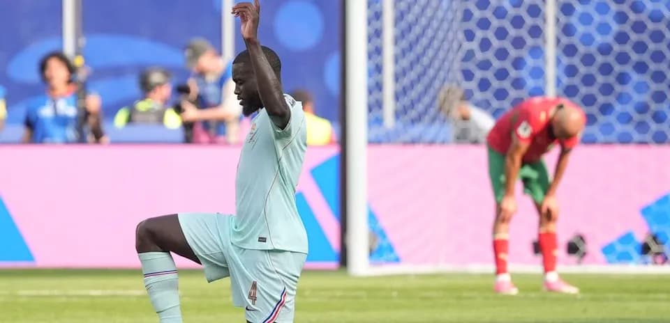 Игрок команды в синей форме на коленях на поле