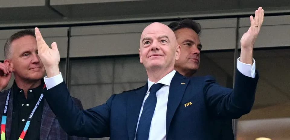 Человек в костюме с логотипом FIFA на трибуне
