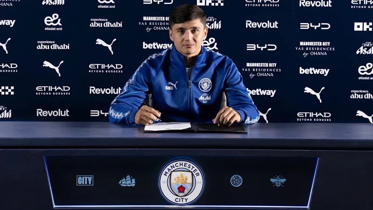 Игрок подписывает контракт за столом с логотипом Manchester City