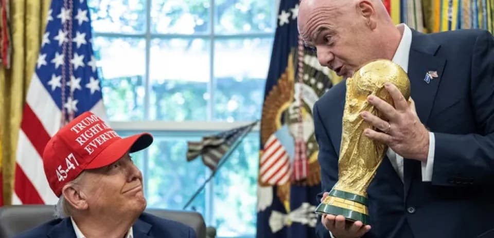 Человек в костюме показывает кубок чемпионата мира