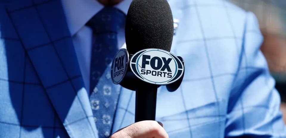 Микрофон FOX Sports в руках мужчины в костюме